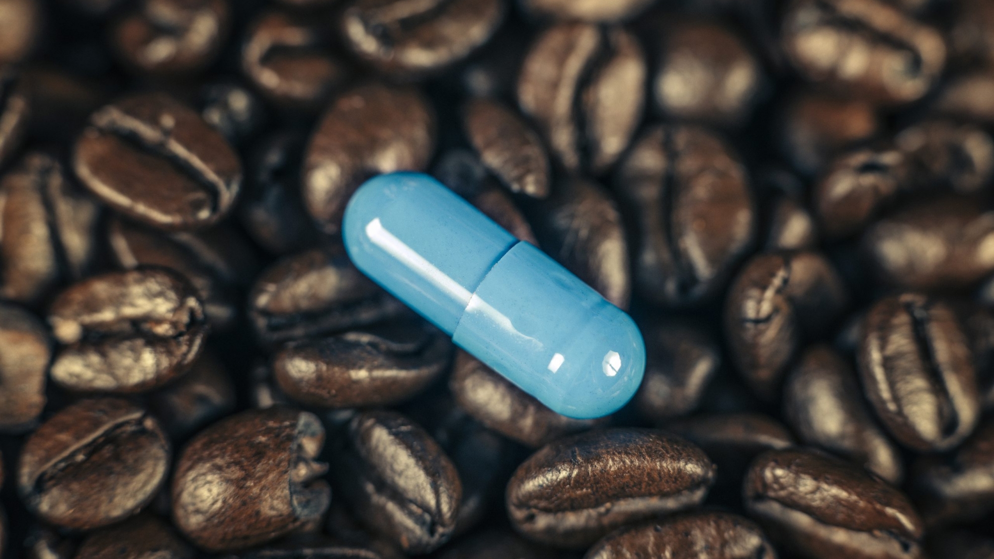 Blue caffeine supplement pill and roasted coffee beans
