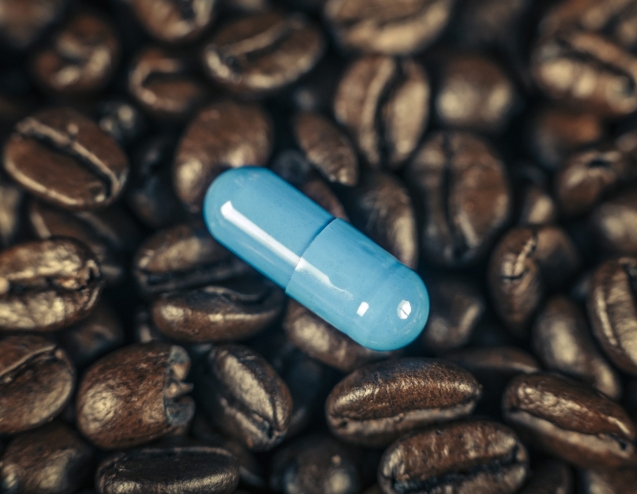Blue caffeine supplement pill and roasted coffee beans